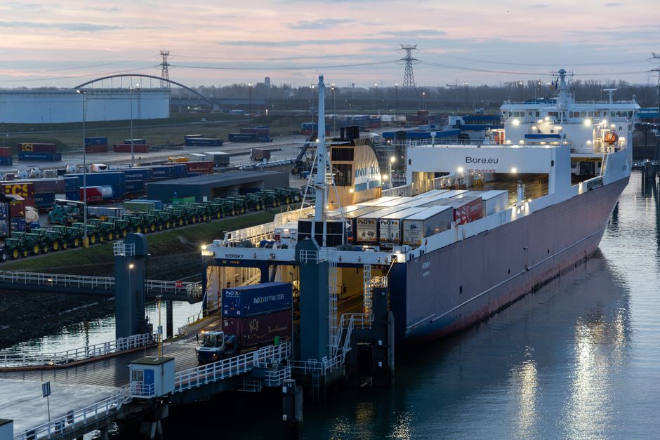 A large cargo ship unloading at Europoort Rotterdam port during dawn, showcasing busy maritime logistics.